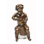 AN ANTIQUE BRONZE CHERUB seated on an alabaster base, overall 17cm in height
