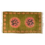 A CONTEMPORARY TIBETAN APPLE GREEN GROUND RUG with two panels of stylistic foliage design and