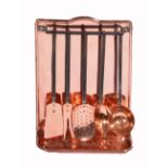 A SET OF FIVE COPPER AND IRON KITCHEN UTENSILS on a wall mounted copper hanging rack, 49.5cm high