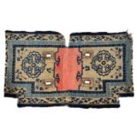 AN ANTIQUE TIBETAN SADDLE RUG with predominantly blue stylistic designs on a white ground 97cm x