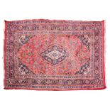 A PERSIAN RED GROUND CARPET, the central blue ground scrolling medallion within a triple border,