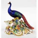 A 19TH CENTURY ENGLISH PORCELAIN PEACOCK on a flower encrusted base, 17cm wide