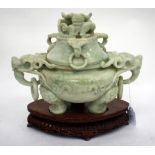 A PALE GREEN COLOURED HARDSTONE CARVED INCENSE BURNER decorated with dragons and standing on three