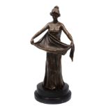 A MODERN BRONZE SCULPTURE OF A GIRL in classical dress and holding out the folds of her dress, the