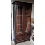 AN EDWARDIAN OAK DISPLAY CABINET with lead glazed doors, further cupboard doors beneath and standing