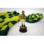 A SMALL SCULPTURE OF A JOCKEY wearing green and yellow checked silks and mounted on a turned