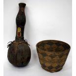 AN AFRICAN TRIBAL LEATHER AND TURNED WOODEN VESSEL with carrying straps and beadwork decoration 59cm