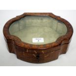 AN OLD LEATHER MOUNTED JEWELLERY BOX with serpentine outline, the lid with bevelled glass insert,