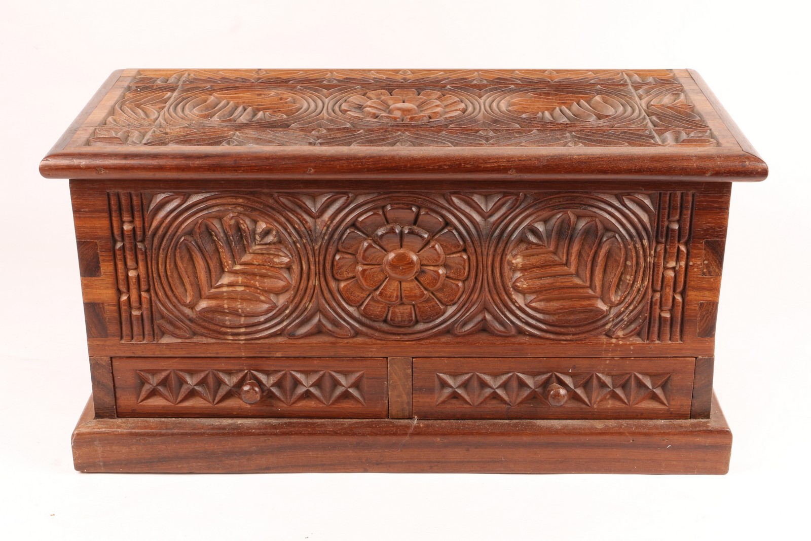 A TANZANIAN CARVED WOODEN CHEST with hinged rising lid and two drawers on a rectangular plinth, 64.