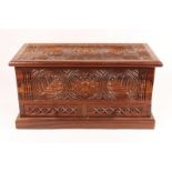 A TANZANIAN CARVED WOODEN CHEST with hinged rising lid and two drawers on a rectangular plinth, 64.
