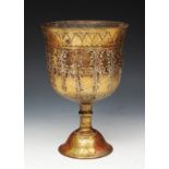 A SOUTH EAST ASIAN BRASS GOBLET with stylised heart and foliate decoration, baluster turned stem and