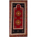 A CAUCASIAN RED GROUND PRAYER RUG with polychrome hooked diamond decoration within a multiple