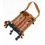 AN AFGHAN SHOULDER BAG with red, yellow and black geometric designs and attached tassels,