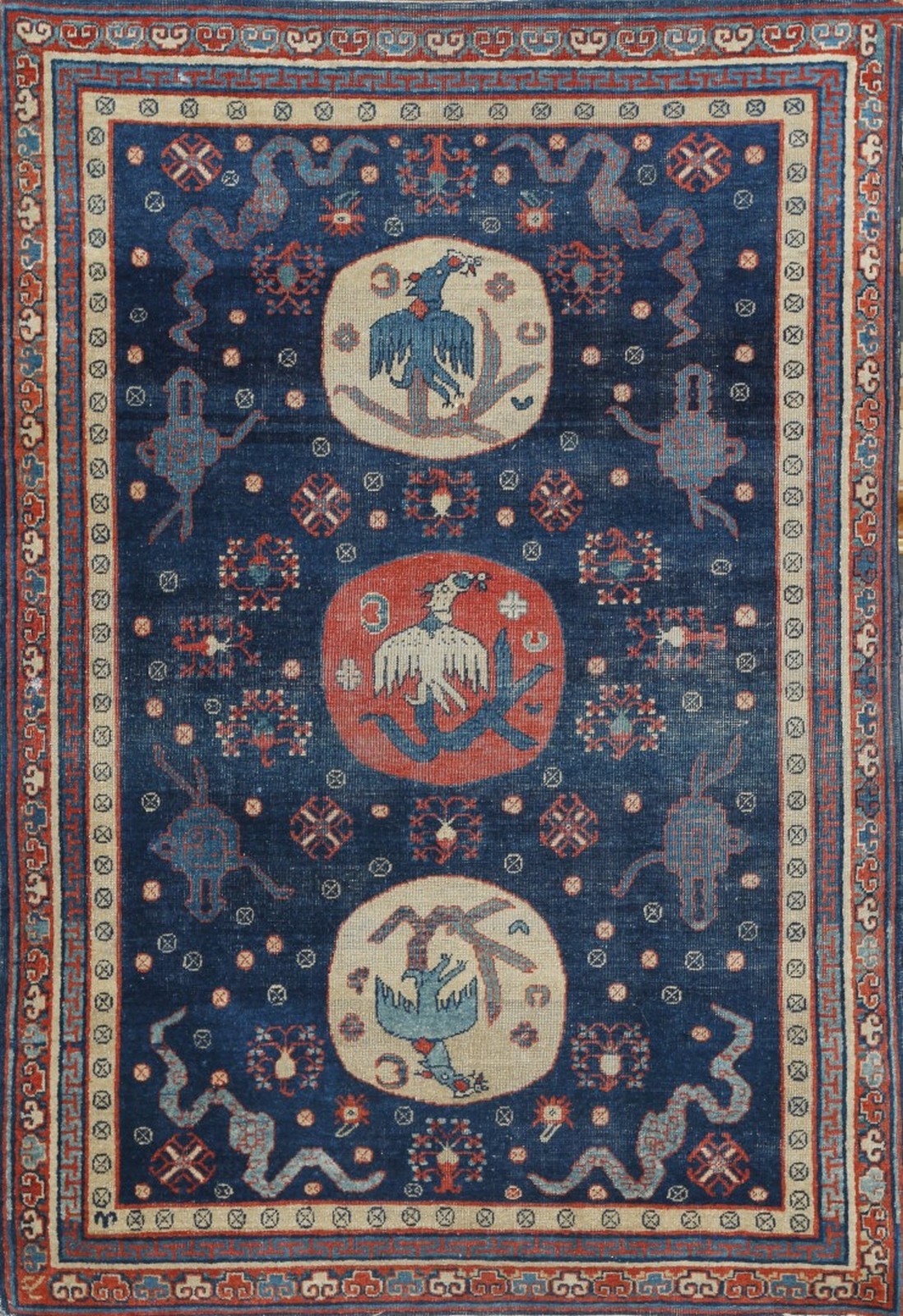 AN ANTIQUE KHOTAN TURKESTAN BLUE GROUND RUG decorated with three circular medallions with