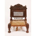 A 19TH CENTURY INDIAN, PUNJAB CARVED WOODEN LOW CHAIR with lattice back and turned supports, 39cm