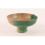 A MIDDLE EASTERN POTTERY STEM BOWL with half green glaze, perhaps Persian, 19.5cm diameter