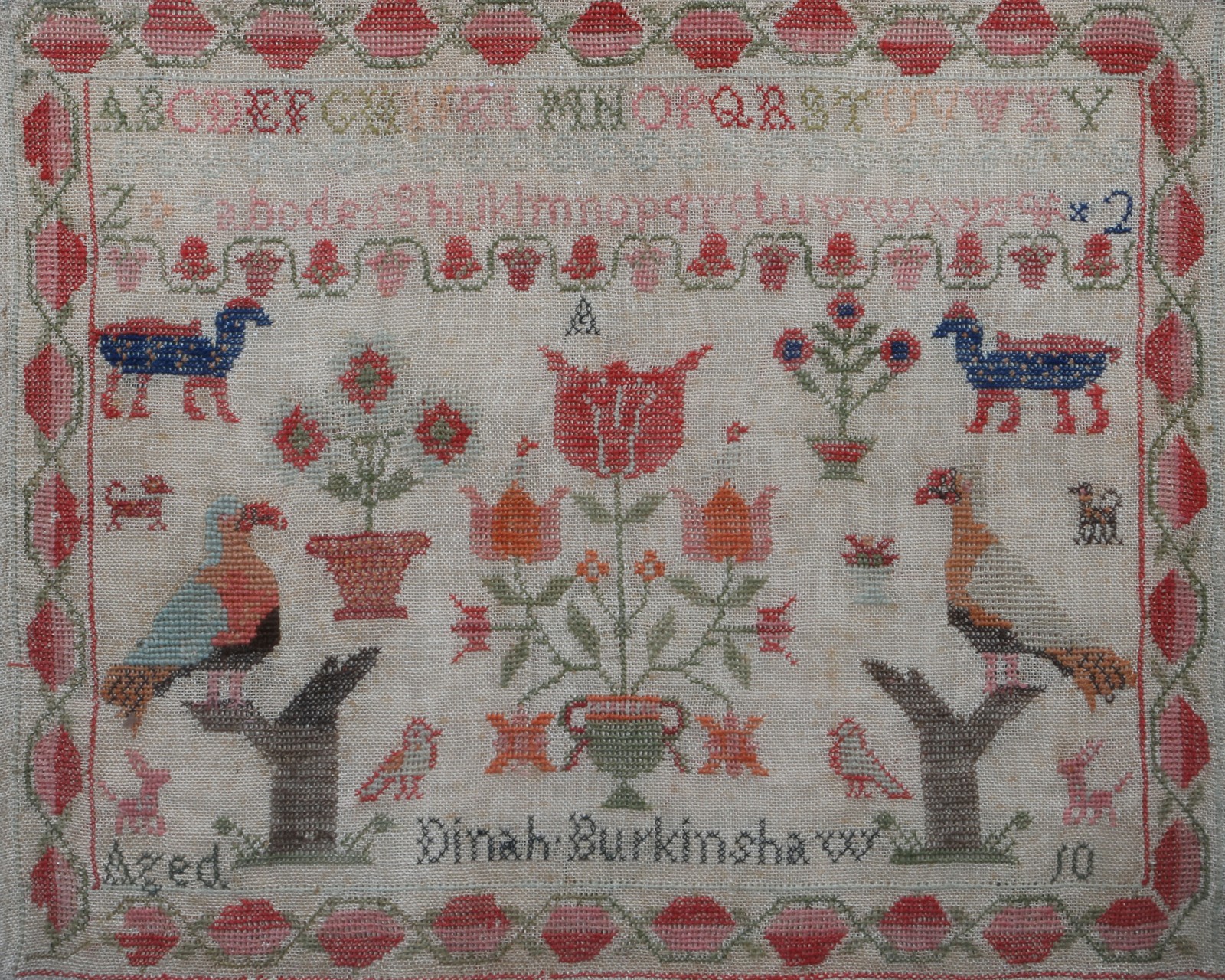 A VICTORIAN GROS POINT NEEDLEWORK SAMPLER with tulip, alphabet and bird decoration by Dinah