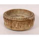 AN ITALIAN ALABASTER AND MARBLE CIRCULAR FONT OR SINK with carved decoration of children at play and