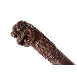 A BURMESE CARVED HARDWOOD WALKING STICK with 'Yuli' head handle and spiral animal motif, 98cm long