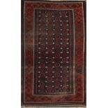 A BELOUCH WINE GROUND RUG decorated with four rows of rosettes within a stylised border, 196 x