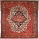 A MALAYER RUST GROUND RUG with a central deep blue ground and foliate medallion within a scrolling