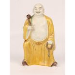 A CHINESE PORCELAIN FIGURE of an Immortal with yellow glazed cloak and a holding a rosary and a