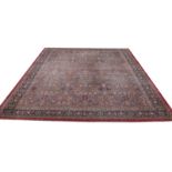 AN OLD KIRMAN LARGE RED GROUND CARPET with repeating polychrome foliate decoration within a multiple