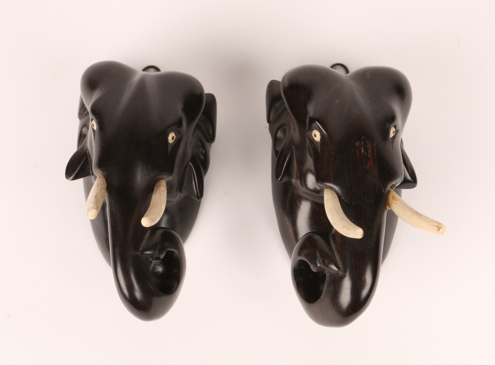 A PAIR OF CARVED EBONY WALL PLAQUES in the form of elephant heads, 13cm high