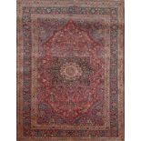 A MASHAD DARK RED GROUND RUG with central radiating medallion within a foliate field and triple