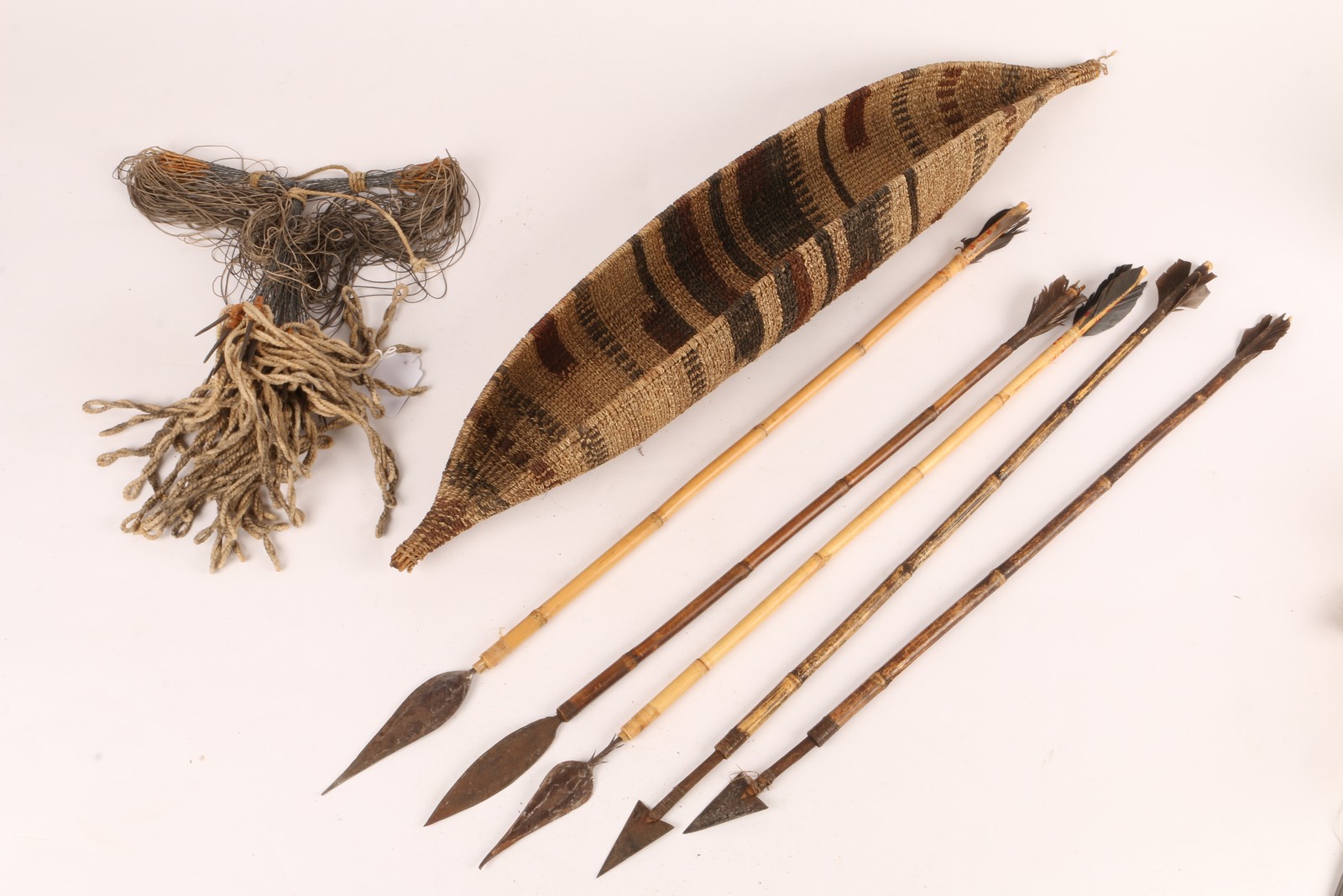 AN ETHIOPIAN FISH BASKET with stylised decoration, 65cm long and five fish spears and a Nigerian