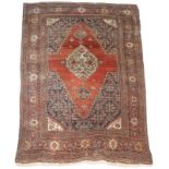 AN ANTIQUE PERSIAN FEREGHAN RUST GROUND RUG, the central medallion with foliate decoration and