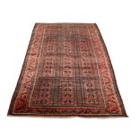 A BELOUCH BRICK RED GROUND RUG decorated three rows of four hooked panels within a scrolling border,