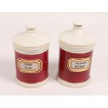 A PAIR OF APOTHECARY CYLINDRICAL JARS AND COVERS with red and white glaze, 26cm high (2)