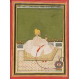 AN INDIAN MINIATURE painted with seated figure holding a flower sprig in one hand and hookah pipe in