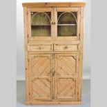 An antique pine glazed standing cabinet,