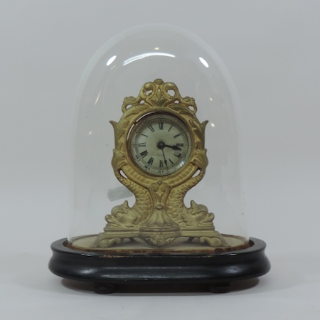 A gilt metal mantel clock, under a dome,