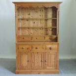 A modern pine dresser, with drawers and cupboards below,