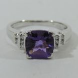 An 18 carat white gold and amethyst ring, with diamond shoulders,