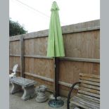 A garden parasol, on a green painted cast iron base,