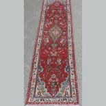 A Persian Hamadan runner, of floral design on a red ground,