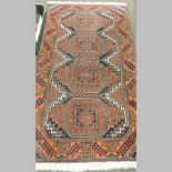 A woollen rug, with three central medallions and geometric designs, on a red ground,