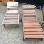 A pair of teak slatted sun loungers,