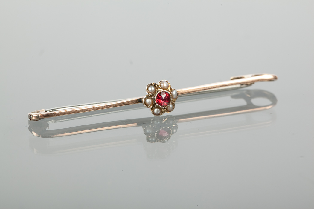 EDWARDIAN RED GEM SET BAR BROOCH set with a central round red gem surrounded by pearls, 6.9mm