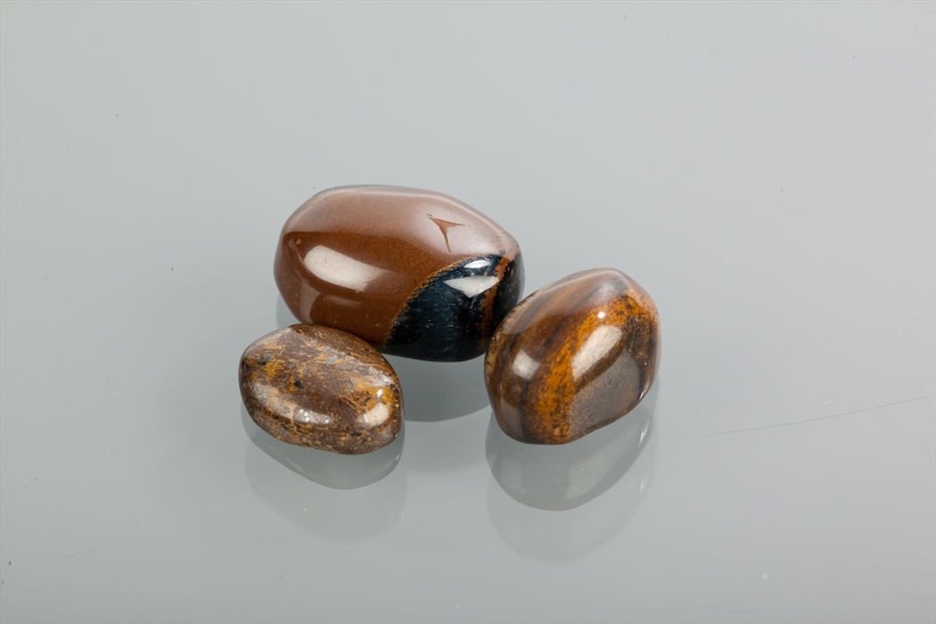 THREE UNMOUNTED TIGERS EYE STONES all of oval form