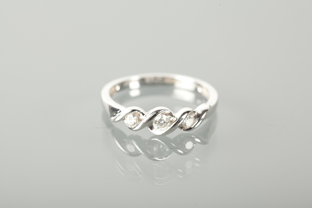 DIAMOND THREE STONE RING set with three brilliant cut diamonds, in a crossover setting, marked 375