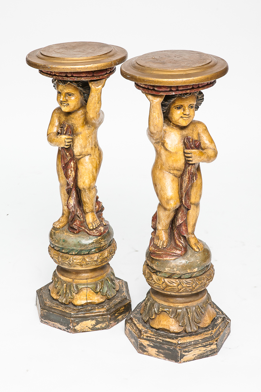 PAIR OF CARVED PAINTED FIGURAL JARDINIERE STANDS
modelled as putti holding robes and circular top