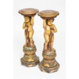 PAIR OF CARVED PAINTED FIGURAL JARDINIERE STANDS
modelled as putti holding robes and circular top