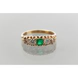 EMERALD AND DIAMOND FIVE STONE RING
with a central square emerald flanked by white and brownish