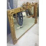 A 19TH CENTURY CARVED GILTWOOD OVERMANTEL, crested with scrolling leaves, above a mirror plate, in