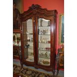 A LARGE FRENCH PROVINCIAL WALNUT ARMOIRE TYPE DISPLAY CABINET, with a shell and leaf crest, on a